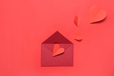 Zarflı kompozisyon ve kırmızı arka planda kağıt kalpler. Sevgililer Günü kutlaması