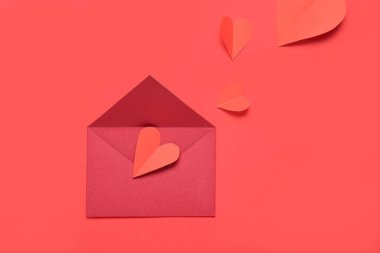 Zarflı kompozisyon ve kırmızı arka planda kağıt kalpler. Sevgililer Günü kutlaması