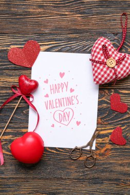 Card with text HAPPY VALENTINE'S DAY and heart shaped decor on wooden background