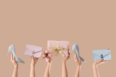 Hediye kutusu, el çantası ve bej arka planda yüksek topuklu ayakkabıları olan kadın elleri. Uluslararası Kadınlar Günü için Alışveriş