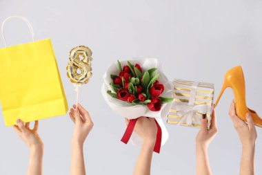 Kırmızı lale buketi, hediye kutusu ve beyaz arka planda alışveriş çantası olan kadın elleri. Uluslararası Kadınlar Günü
