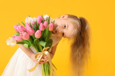 Sarı arka planda bir buket güzel lalesi olan sevimli küçük bir kız. Uluslararası Kadınlar Günü