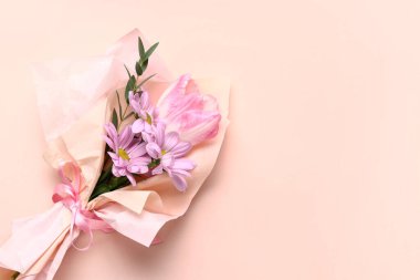 Pembe arka planda ambalaj kağıdına sarılmış küçük bir buket güzel bahar çiçeği. Uluslararası Kadınlar Günü