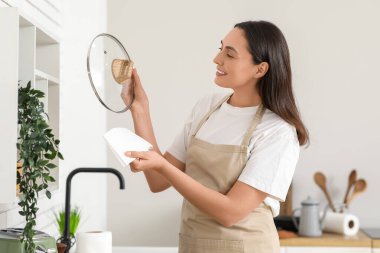 Mutfakta bulaşık takımlarını kağıt havlularla silen genç ve güzel bir kadın.