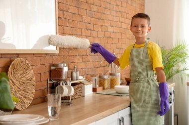 Mutfakta toz bezi ile mobilyaları temizleyen şirin bir çocuk.