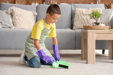 Evinde faraş ve fırça temizleme halısı olan sevimli küçük çocuk, yakın plan.