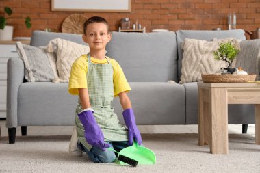 Evinde faraş ve fırça temizleme halısı olan sevimli küçük çocuk, yakın plan.