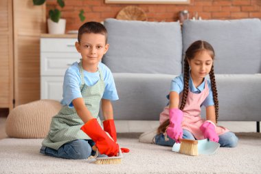 Küçük çocuk ve kız kardeşi evde halı temizliyor.