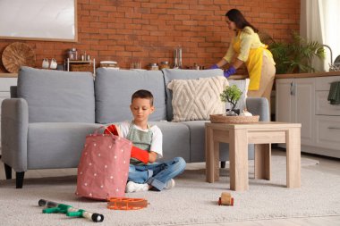 Sevimli küçük çocuk, evde temizlik işlerinde annesine yardım ediyor.