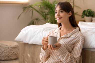 Pijamalı, evinde çay olan güzel, genç ve mutlu bir kadın.