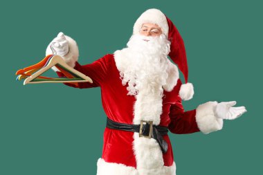 Farklı elbiselere sahip Noel Baba yeşil arka planda asılı.