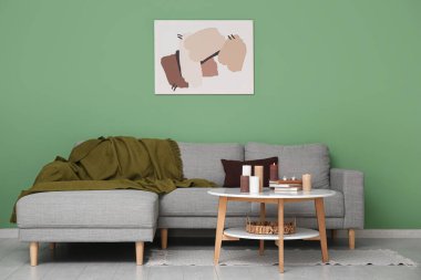 Oturma odasının içinde kanepe, kitaplar ve yanan mumlar var.