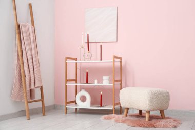 Odanın içinde raf ünitesi, puf ve yanan mumlar.