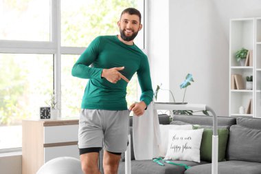 Sportif genç adam evdeki koşu bandını işaret ediyor.