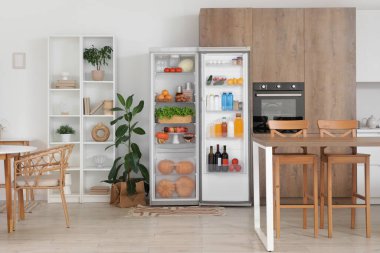 Ev bitkileriyle dolu modern mutfak ve taze yiyeceklerle dolu açık buzdolabı.