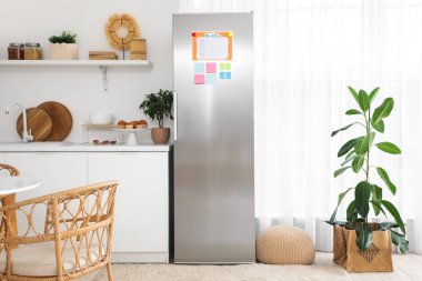 Modern mutfakta yapışkan notları ve yemek planı olan bir buzdolabı.