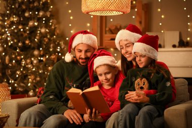 Mutlu aile akşamları evde Noel öyküsü okuyor.