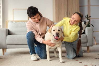 Mutlu kız ve erkek kardeş ve şirin Labrador köpeği evde yerde oturuyor.