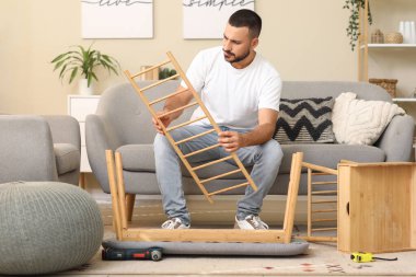 Genç adam evdeki bankta toplanıyor.