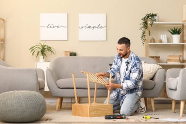 Genç adam evde ahşap masa kuruyor.