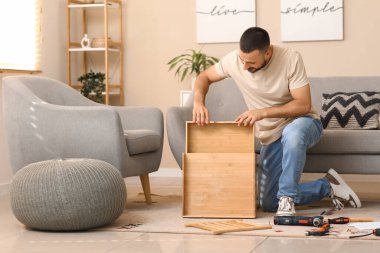 Evdeki çekmecede ahşap masa montajı yapan genç adam.