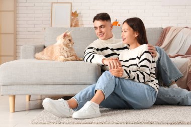 Oturma odasında sevimli Maine Rakun kedisi olan güzel bir çift.