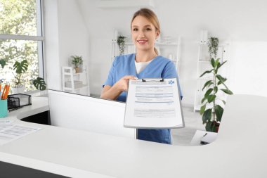 Klinikteki resepsiyonda sağlık sigortası olan kadın stajyer.