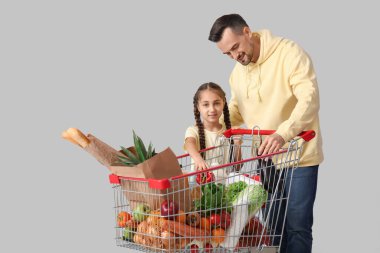 Genç mutlu baba ve kızı gri arka planda alışveriş arabasıyla