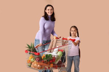 Güzel, genç, mutlu anne ve kızı bej arka planda alışveriş arabalarıyla