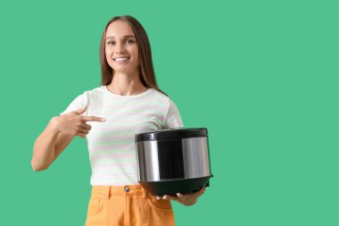 Yeşil arka planda çoklu fırını işaret eden genç bir kadın.