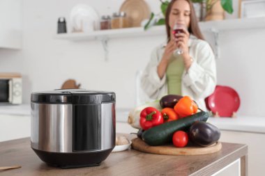 Sebzeli çoklu tencere mutfakta şarap içen kadına karşı, yakın plan.