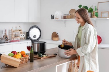 Mutfakta yemek hazırlayan çoklu fırınlı genç bir kadın.