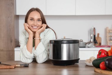 Mutfaktaki masada çoklu ocağı olan genç bir kadın.
