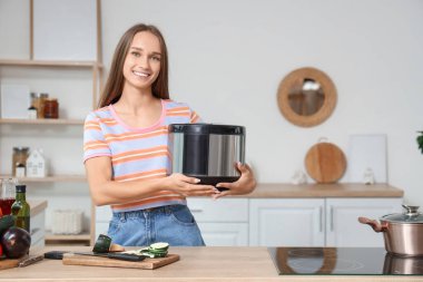 Mutfakta çoklu fırını olan genç bir kadın.