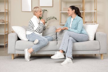 İşitme cihazlı kadınlar evdeki kanepede oturuyorlar.