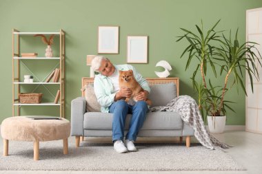 Evdeki kanepede oturan sevimli Pomeranya köpeği olan mutlu son sınıf öğrencisi.