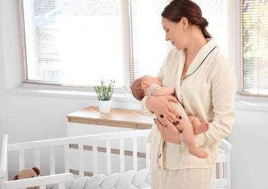 Mutlu anne, tatlı, uyuyan bebeğini pencerenin yanında tutuyor.