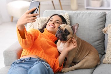 Fransız bulldoglu güzel bir kadın evdeki kanepede selfie çekiyor.