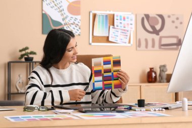 Ofiste tablet ve renk paletleriyle çalışan genç bayan grafik tasarımcısı