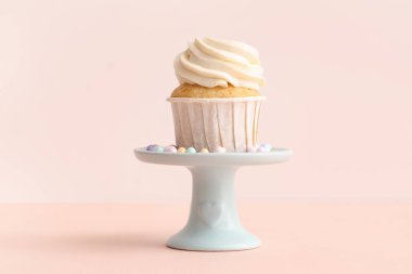 Tatlı doğum günü pastası ve bej arka planda serpiştirilmiş şekerlemelerle dur