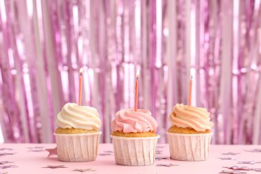 Tatlı doğumgünü kekleri yanan mumlar ve pembe arka planda süslemeler