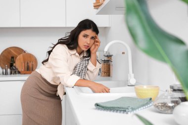 Mutfakta baş ağrısı çeken yorgun genç bir kadın. Stres kavramı