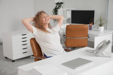 Genç ve güzel bir kadın ofiste koltukta dinleniyor. İzin günü kavramı