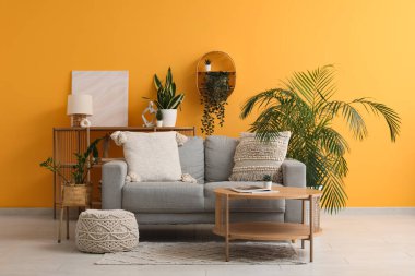 Modern oturma odasının içinde masa ve çiçekli gri bir kanepe.