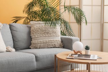 Modern oturma odasının içinde ahşap masalı gri kanepe.