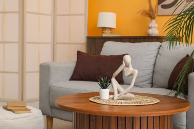 Modern oturma odasının içinde ahşap masalı gri kanepe.