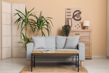 Modern oturma odasının içinde ahşap masa ve tuvalet olan gri kanepe.