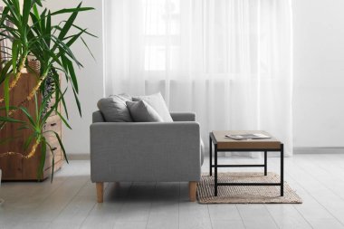 Modern oturma odasının içinde ahşap masalı gri kanepe.