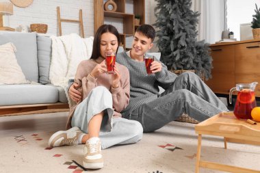 Mutlu çift sürahi ve lezzetli şarap kadehleriyle ahşap tepside evde oturuyorlar.