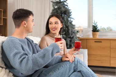 Evdeki koltukta oturmuş lezzetli bir kadeh şarap içen mutlu bir çift.